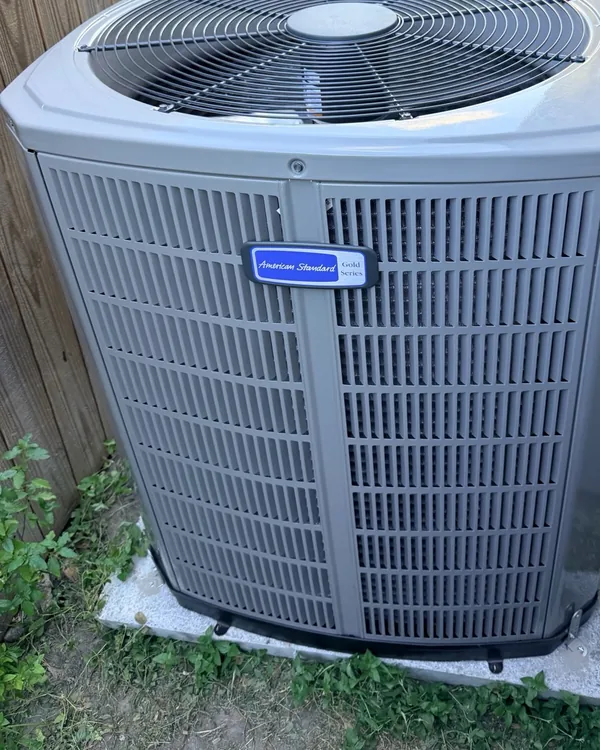 New American Standard Gold Series outdoor unit beside a wood fence, with the badge facing the camera