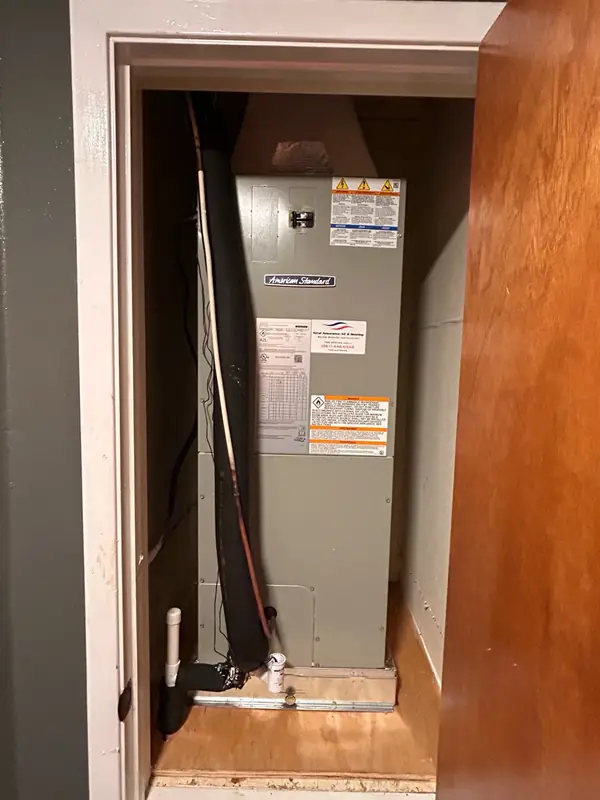 American Standard air handler installed in a closet, with the refrigerant lines insulated and the condensate drain piped
